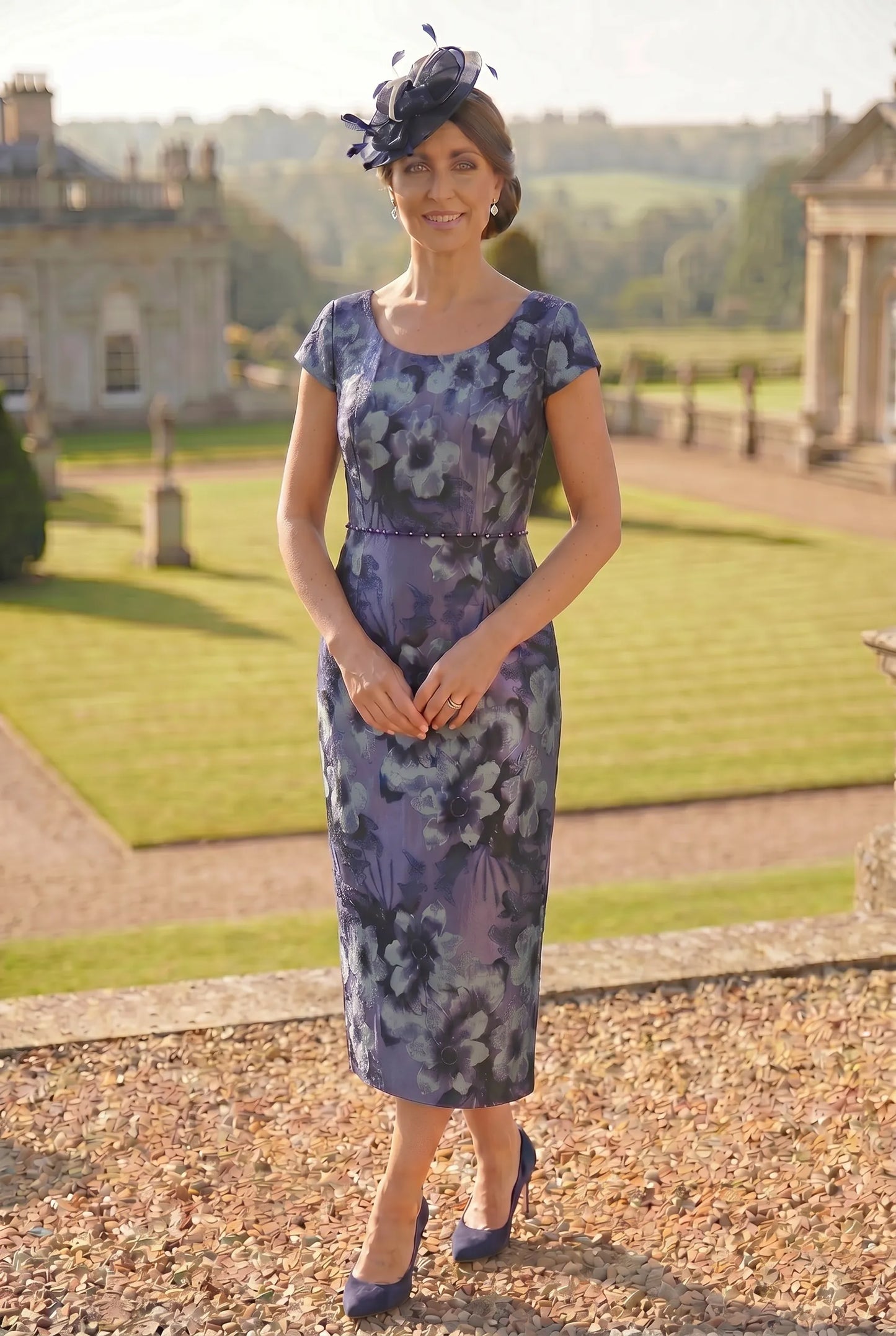 Woman in a floral mother of the bride dress standing outdoors with a scenic background