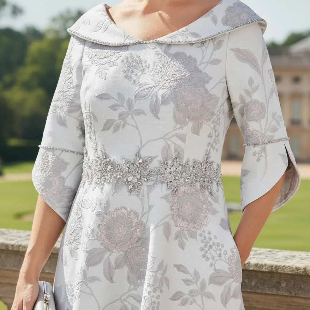 Close-up of Lizabella 2370 silver Mother of the Bride dress showing sparkling collar detail, embellished bell cuffs and jacquard floral texture.