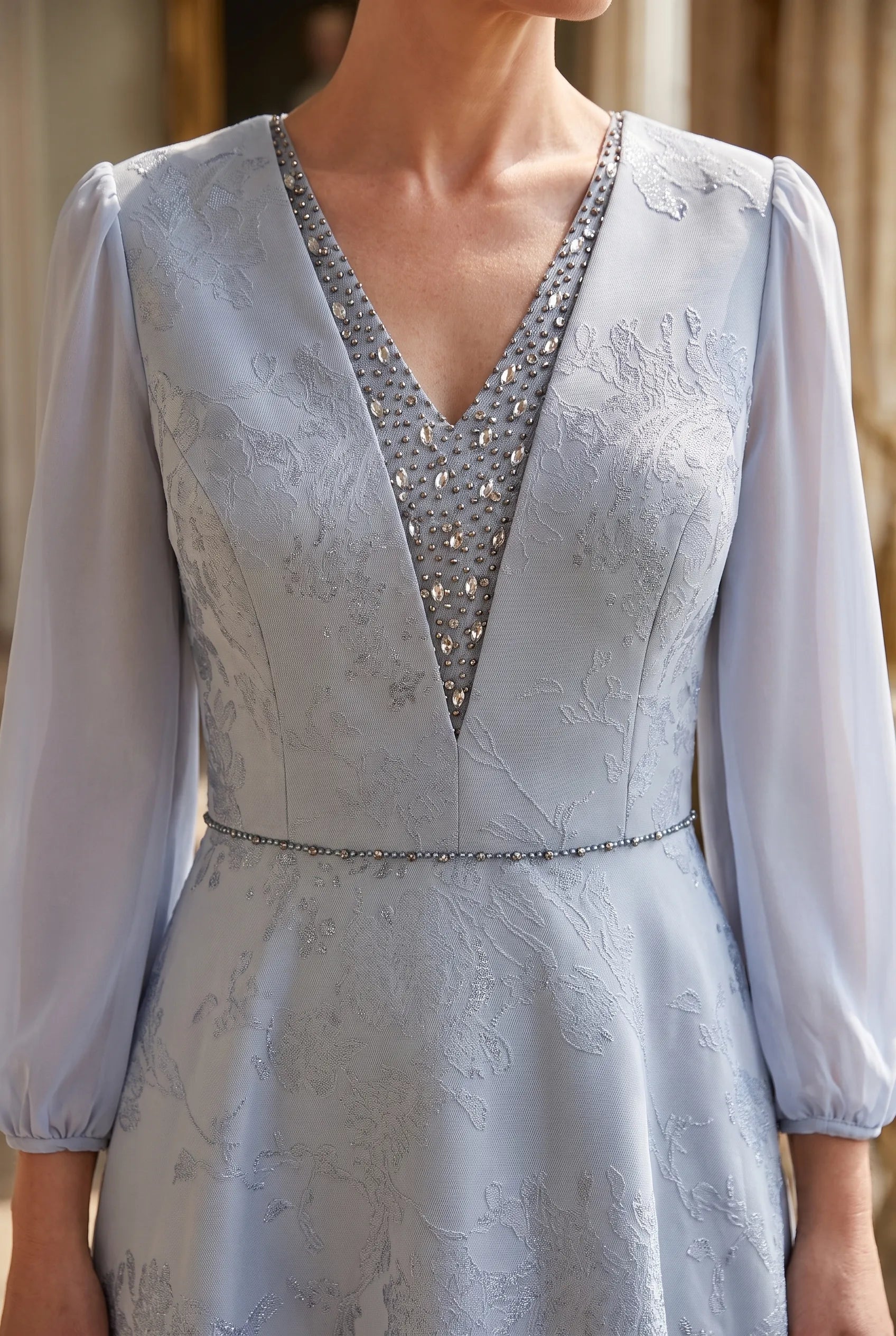 Close-up of the crystal embellished V-neckline and beaded waist detail on the Lizabella 2808 dress