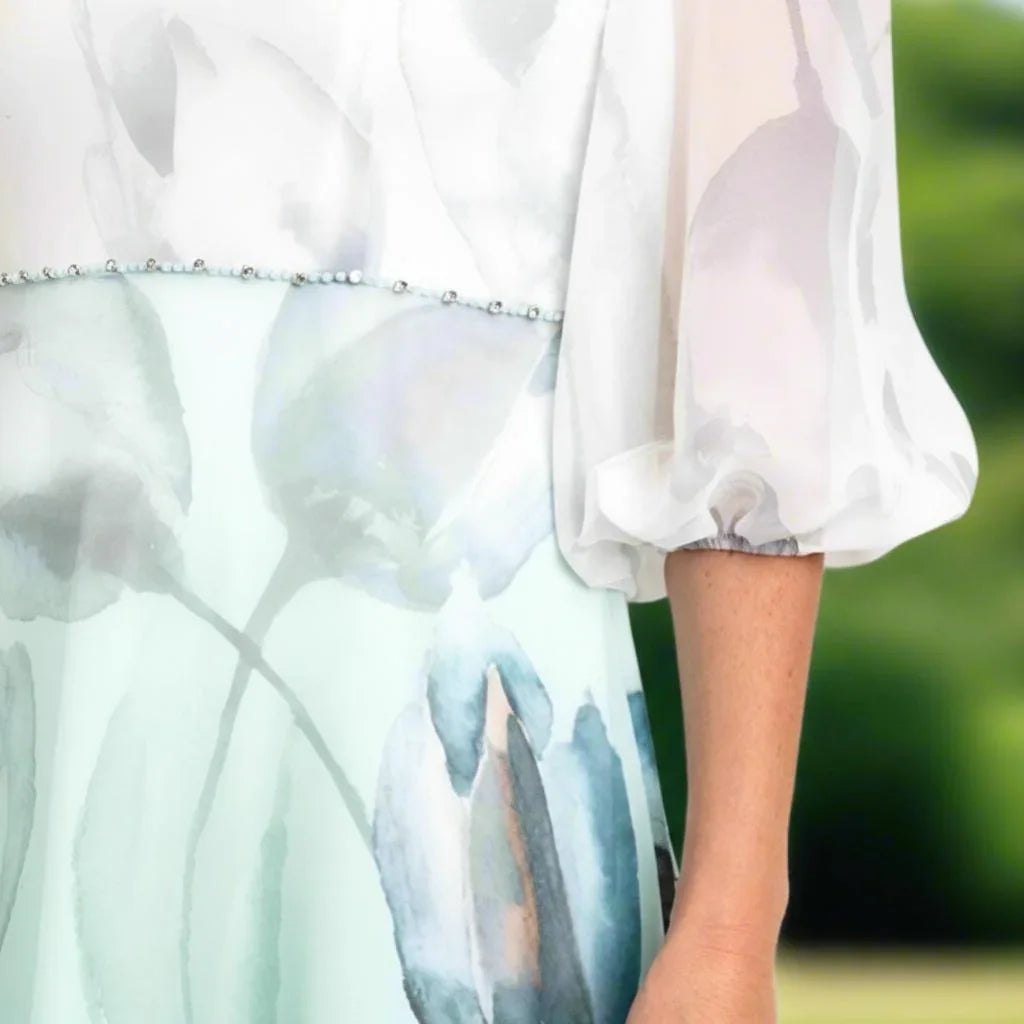 zoomed view of a Lizabella 2838 sage green Mother of the Bride dress with floral chiffon, draped neckline and elegant A-line silhouette.