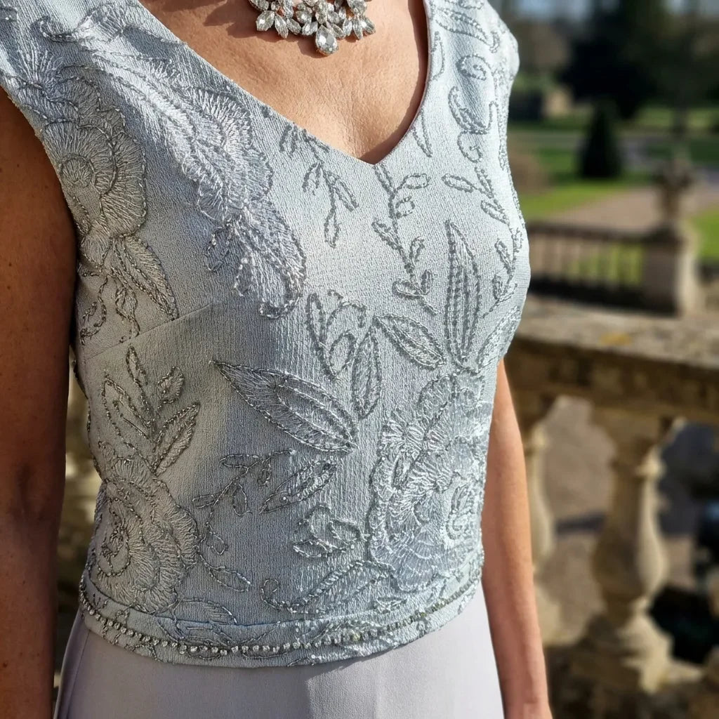 Back view of Lizabella Dress 7168 with matching embroidered fur‑trimmed layer and pearl‑detailed cuffs.

