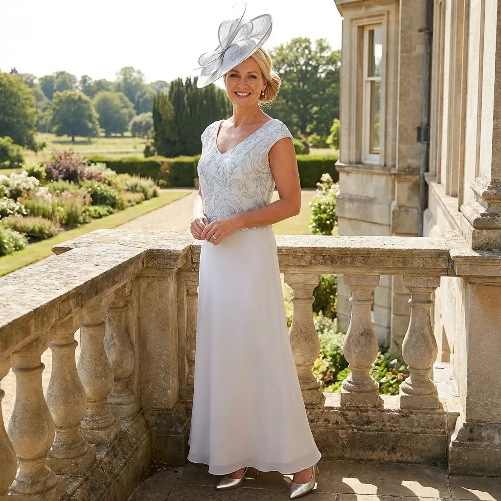 Close‑up of Lizabella Dress 7168 showing detailed embroidery, pearls, rhinestones and soft silver‑blue V‑neck bodice.

