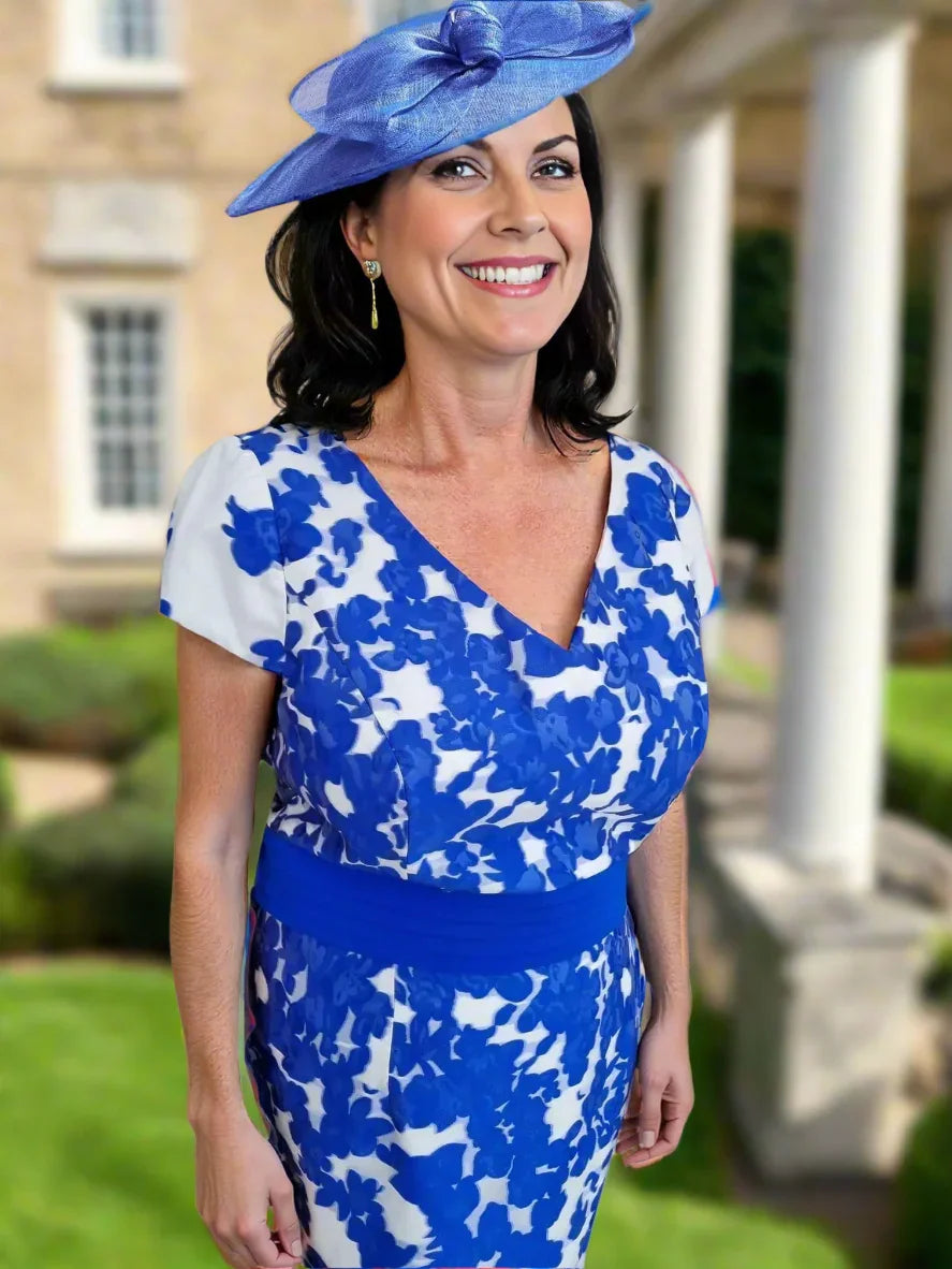 Woman wearing a blue and white floral dress with a matching hat on a white background