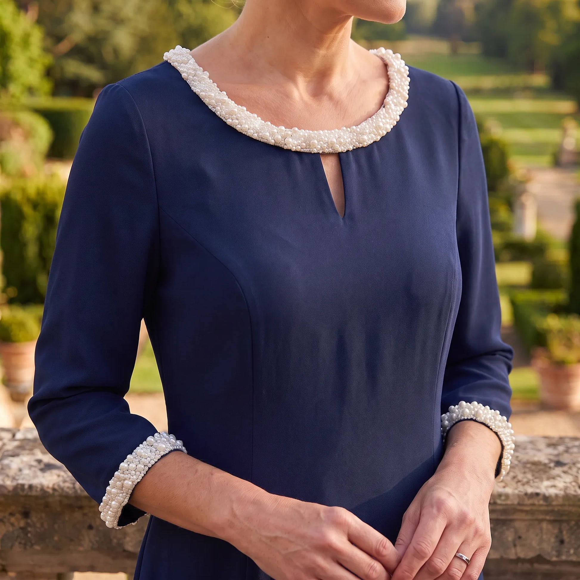 Close-up of the pearl trimmed neckline and keyhole detail on the navy Lizabella 2583 dress