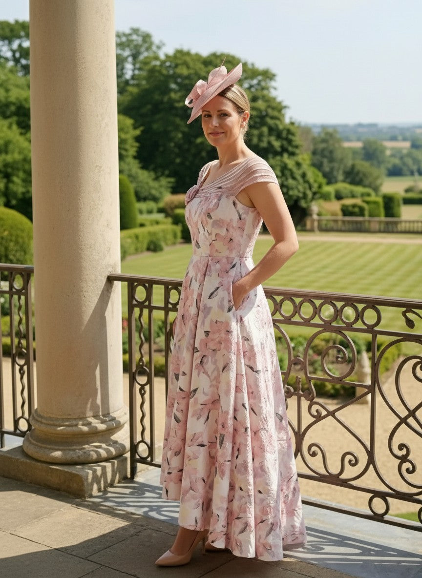 Pastel pink Couture Club 8G1F9 Mother of the Bride dress with dipped hem and pockets photographed outdoors.