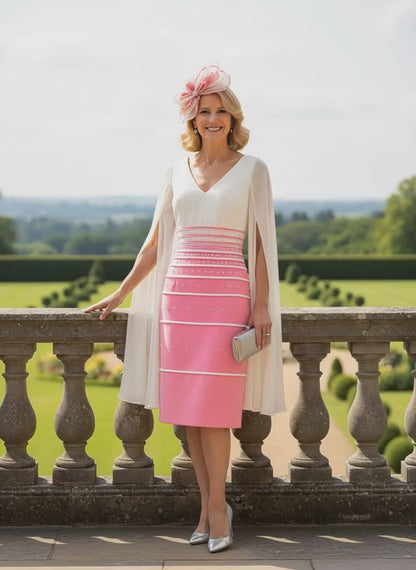 Woman in a pink veni infantino dress with a white cape standing on a balcony with a scenic background
