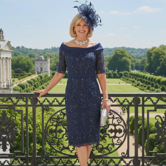 Woman in a navy Veni Infantino dress with lace details standing on a balcony with a scenic background