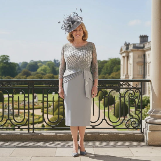 Woman in a stylish Silver grey mother of the bride dress and hat standing on a balcony with a scenic 