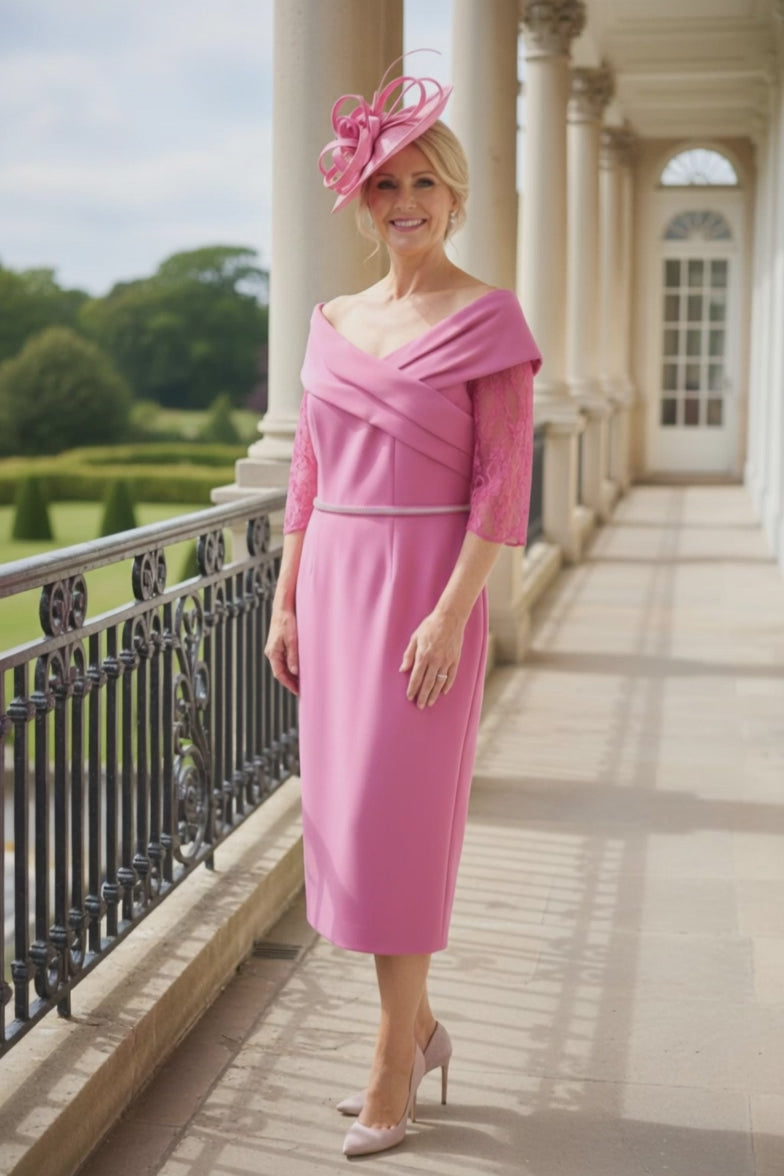 Video of a woman in a Gabriella sanchez pink mother of the bride dress and matching pink fascinator standing on a balcony.