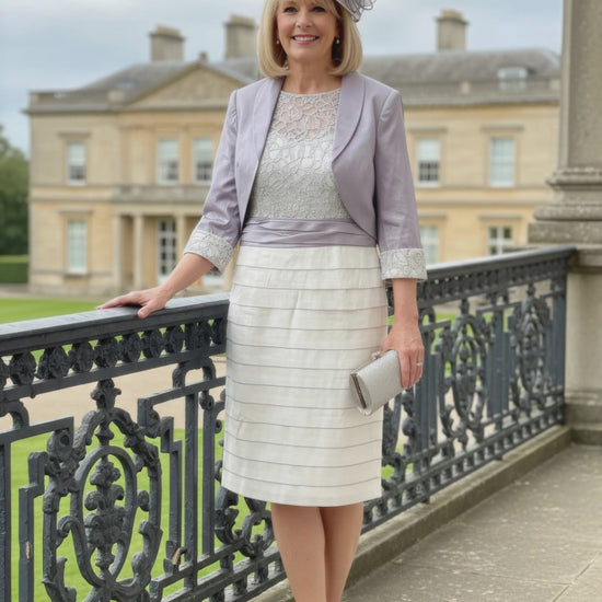Woman in formal 2 piece outfit in lilac from ispirato standing on a balcony with a building in the background