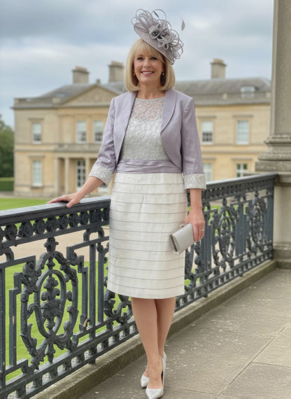 Woman in formal 2 piece outfit in lilac from ispirato standing on a balcony with a building in the background