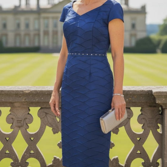 Woman in a COBALT blue LIZABELLA dress with a matching hat standing outdoors. Signature Dress