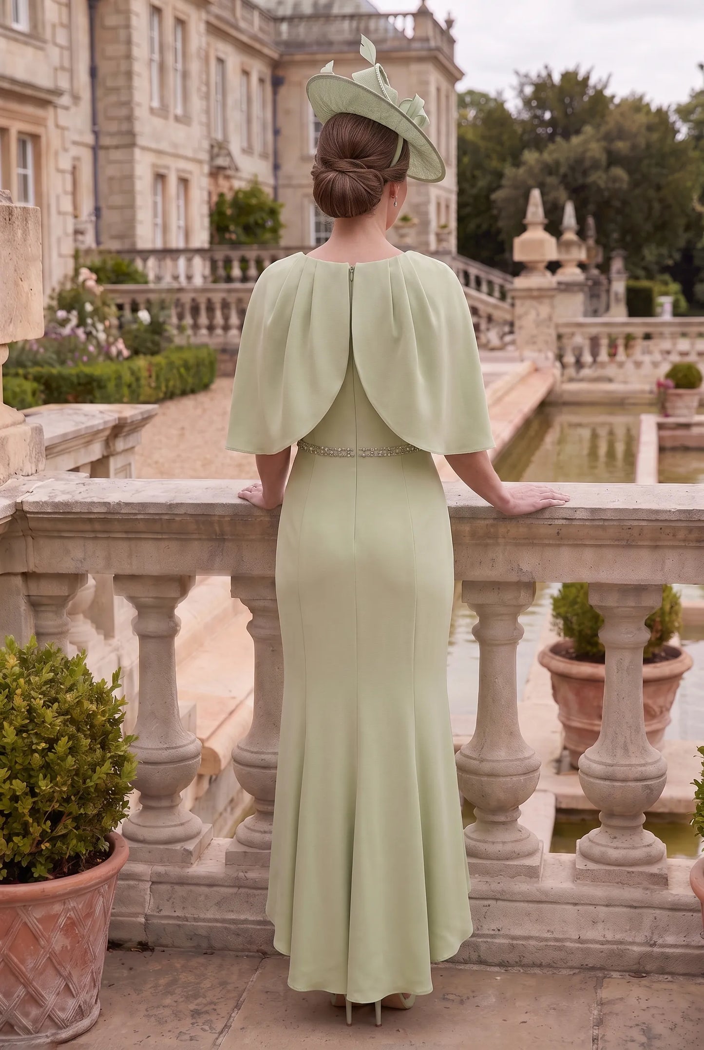 Rear view of the Sage Green Mother of the Bride Dress by Couture Club 7G178 showing the flowing cape and fishtail hem.