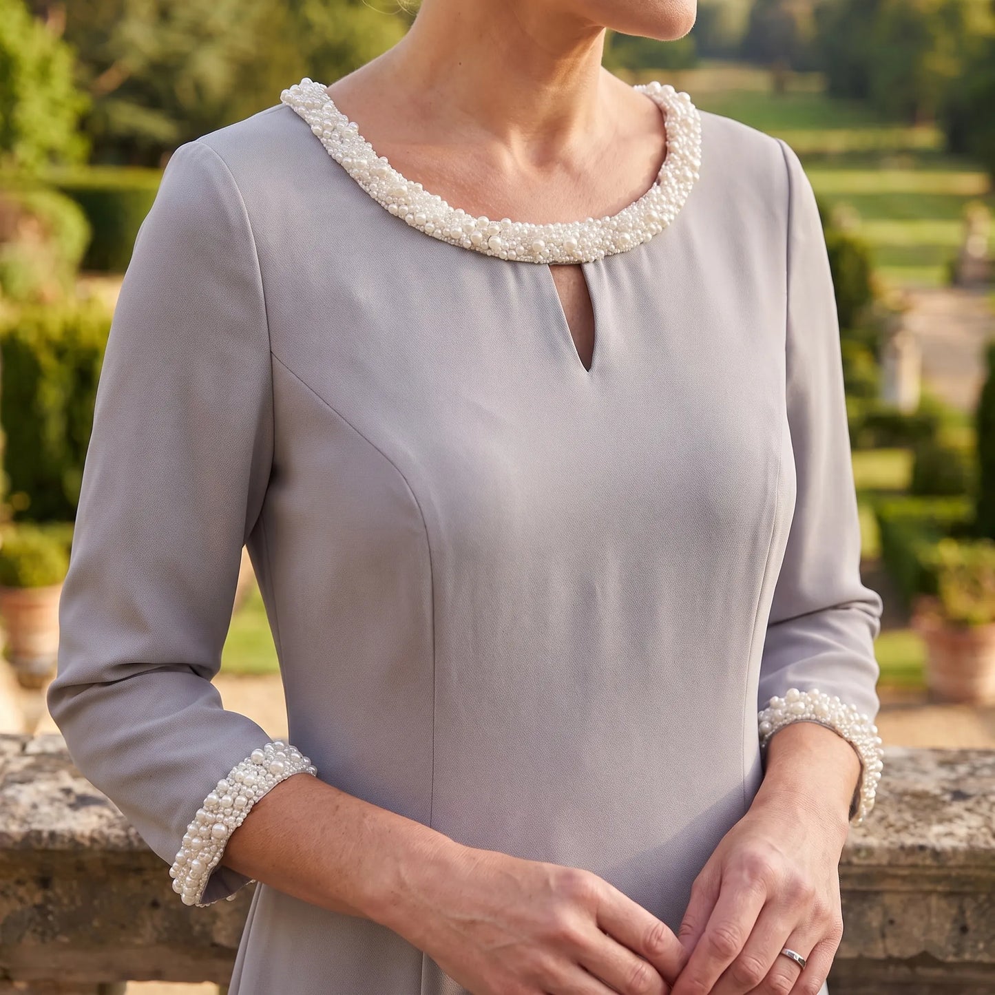 Close-up of the pearl trimmed neckline and keyhole detail on the silver Lizabella 2583 dress