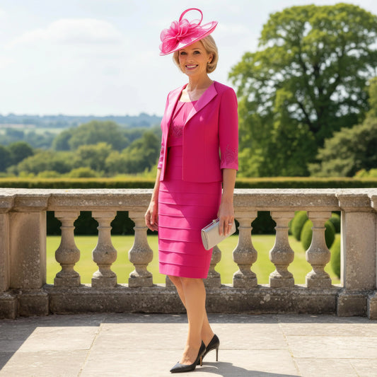 Woman in a pink veni infantino outfit with a matching hat standing outdoors.