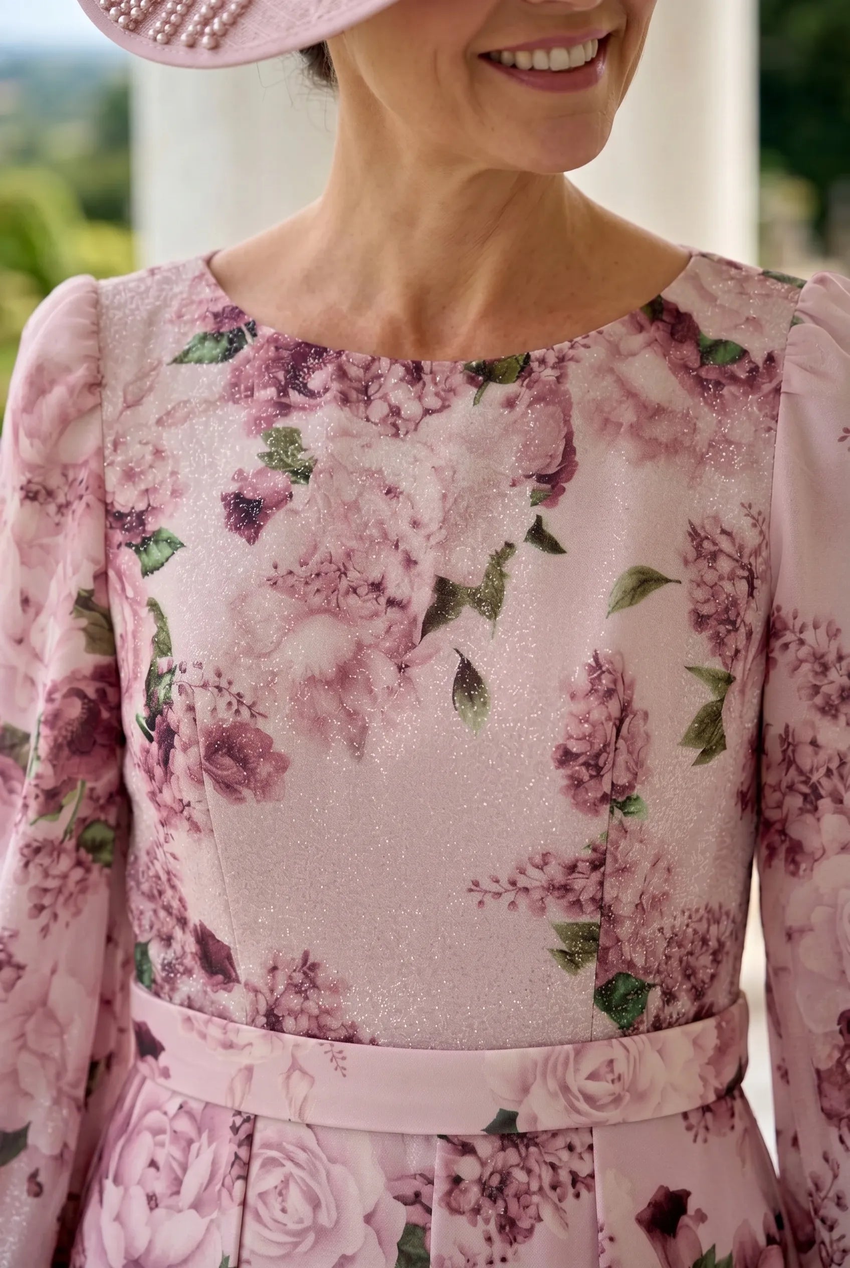 Woman wearing a veromia pink floral mother of the bride dress with a blurred background