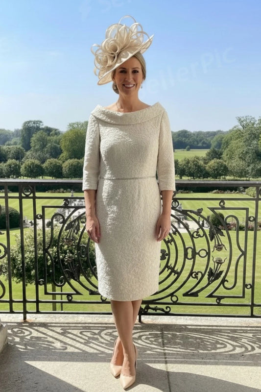 Woman in a champagne beige mother of the bride  dress with a decorative beige fascinator standing on a balcony with a scenic background.